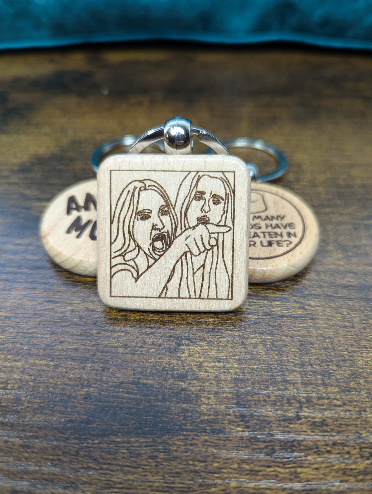 square wooden keychain with an engraved image of a woman screaming and pointing