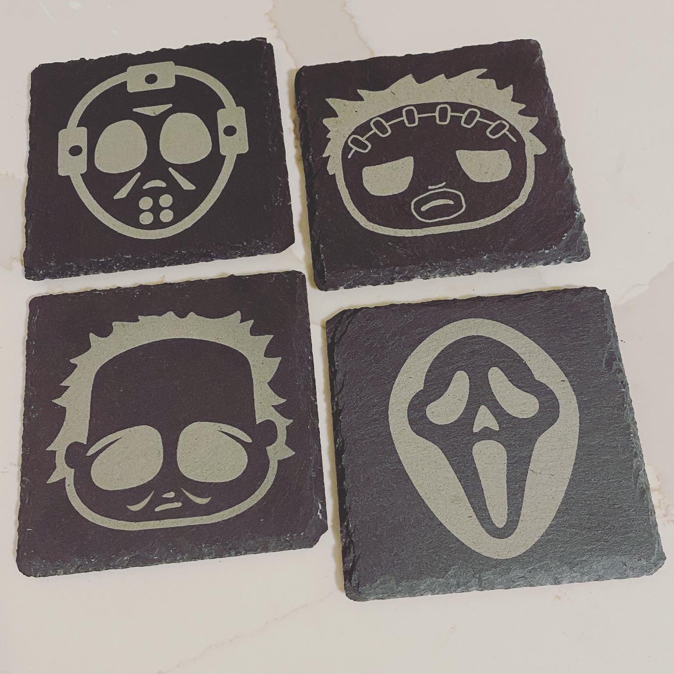 Set of 4 drink coasters with horror film characters etched on them: Jason Vorhees, Michael Meyers, Leatherface, and Ghostface