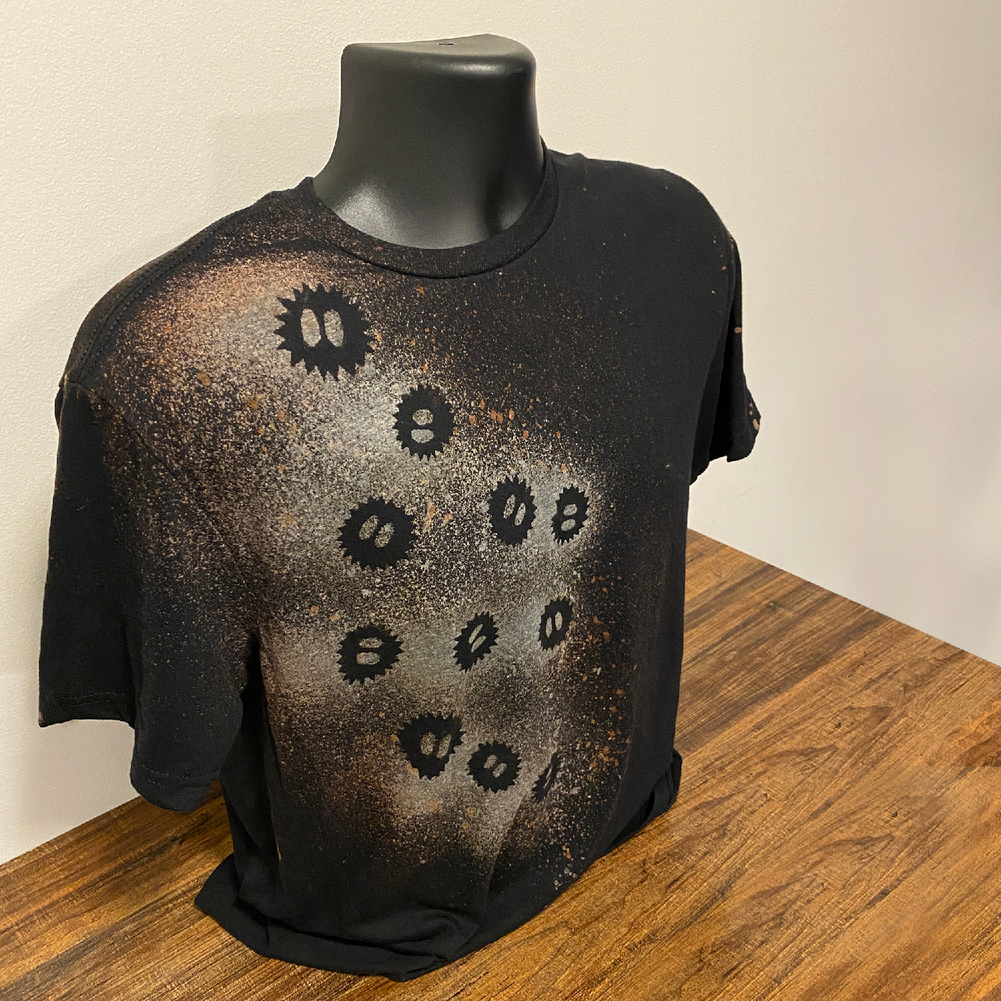 A black shirt on a shirt form with a bleach soot sprite design