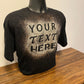 Black shirt that says "your text here" on it, made with bleach. The shirt is on a shirt form, which is sitting on a wood table.