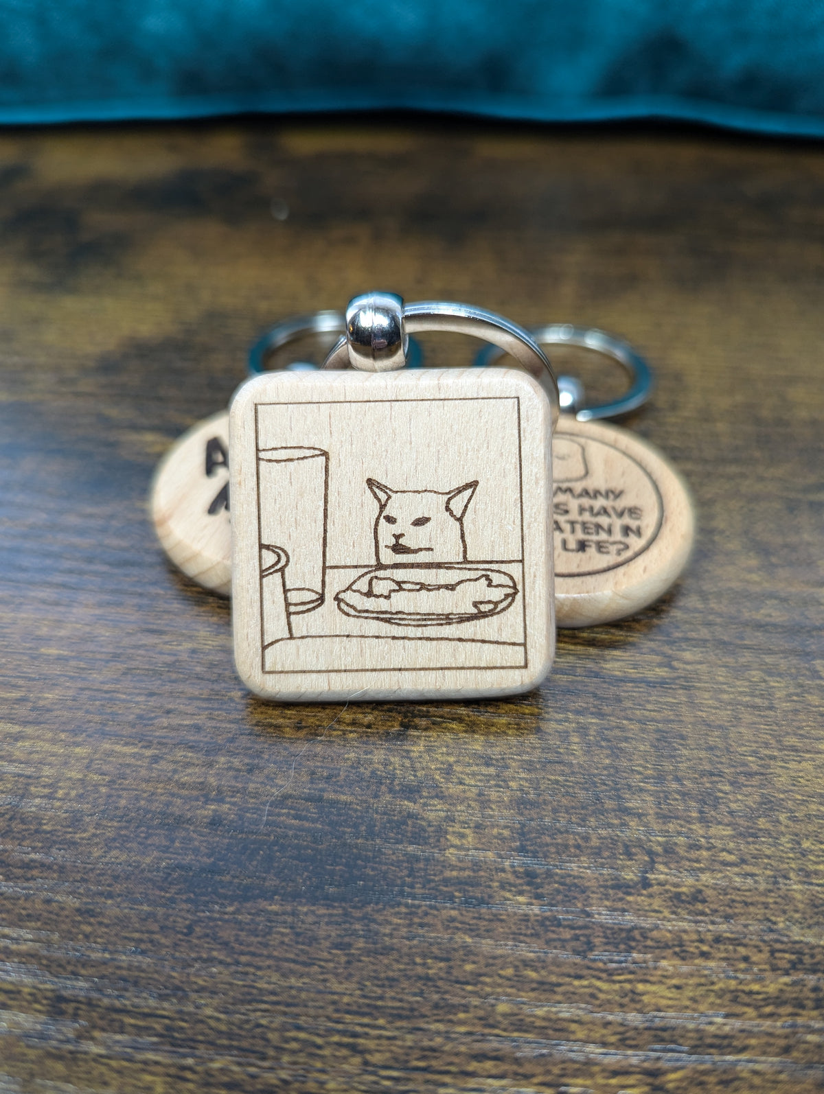 square wooden keychain with an engraved image of the Smudge the salad cat