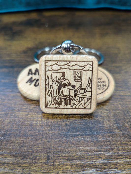 square wooden keychain with an engraved image of the "this is fine" dog in a house on fire 